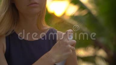 一位美丽的年轻女子用防蚊剂喷在皮肤上的超慢镜头。 一片热带